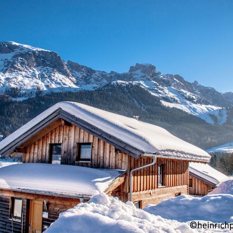 Ferienhaus im Schnee, umgeben von mächtigen Bergen