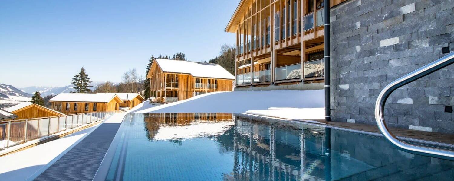 Modern, snow covered wooden chalets with private outdoor pool.