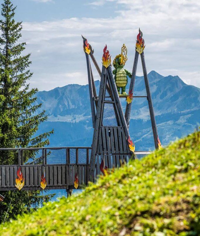 Riesige Klettergerüst für Kinder mit feuerspeiendem Schmidolin, dem Drachen Maskottchen der Schmittenhöhe.