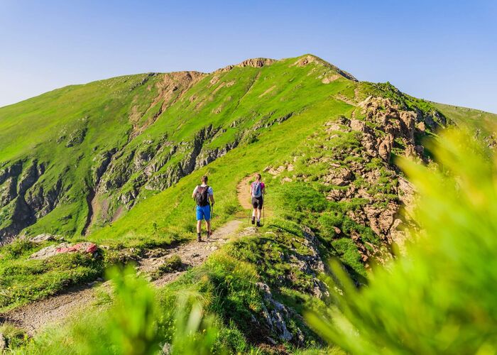 Zwei Wanderer genießen den Aufstieg über grüne Almwiesen in Kärnten