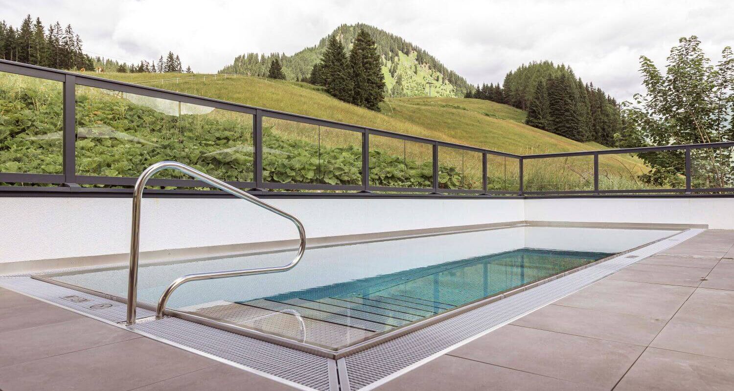 Sun terrace with outdoor pool and views of green meadows and mountain peaks