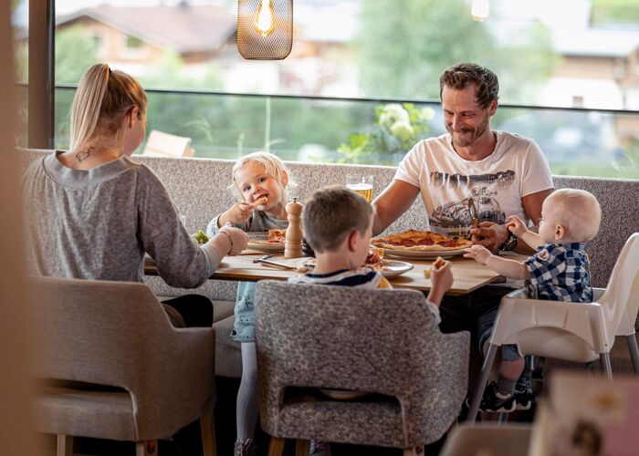 Family enjoying a meal together in the cosy living and dining area at Carpe Solem Rauris.