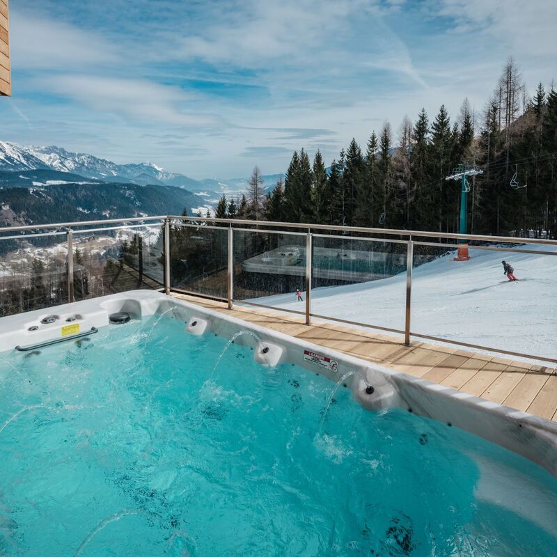 Ein luxuriöser Außen Whirlpool bietet einen atemberaubenden Blick auf die verschneiten Berge und die Skipiste.