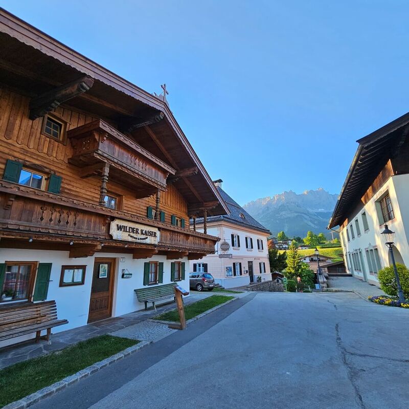 Goinger village square with old farmhouse and view of the Wilder Kaiser.