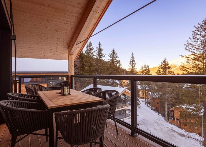 Balkon eines Naturchalets auf der Turracher Höhe im Winter mit Blick auf verschneite Bäume und die winterliche Berglandschaft.