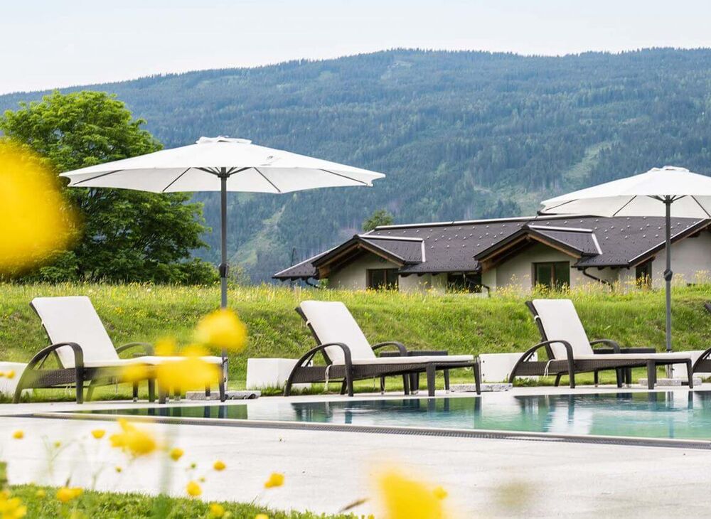 Outdoor Pool mit Sonnenliegen und Schirmen in der Tauernresidence Radstadt