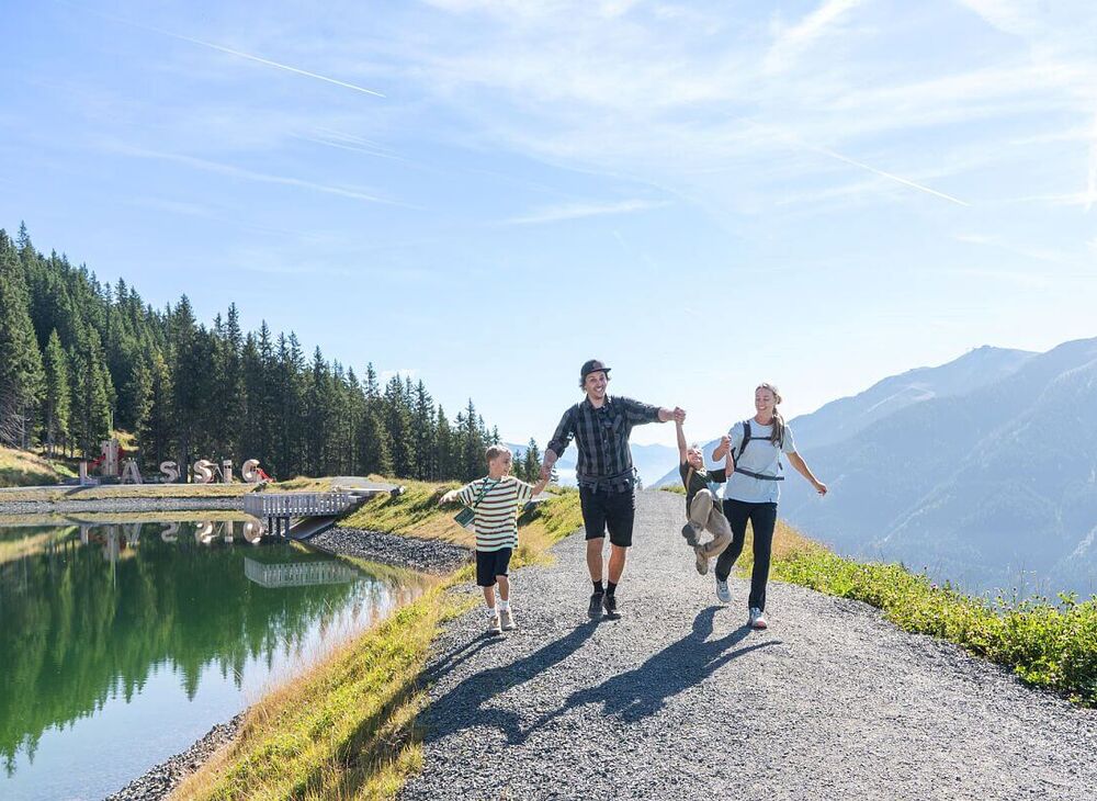 Familie wandert unbeschwert am Speicherteich in Saalbach Hinterglemm