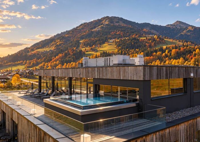 Außenansicht des Bergresort Westendorf mit Pool und herbstlicher Berglandschaft