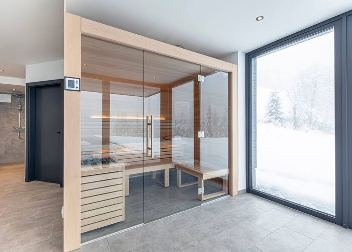 Wellnessbereich mit Sauna und Ausblick auf märchenhafte, verschneite Winterlandschaft