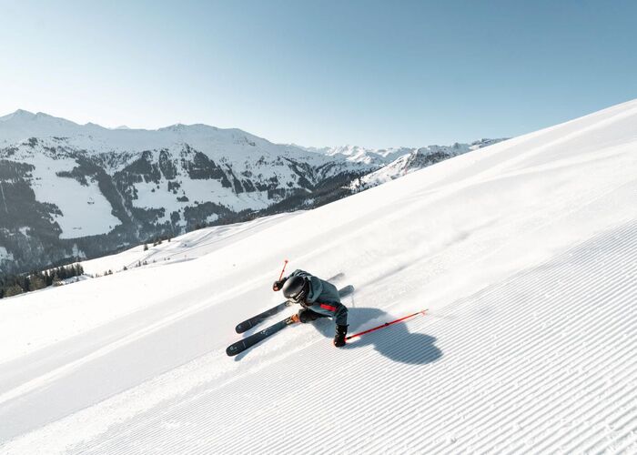 Skifahrer beim Carven auf einem einsamen, frisch präparierten Hang