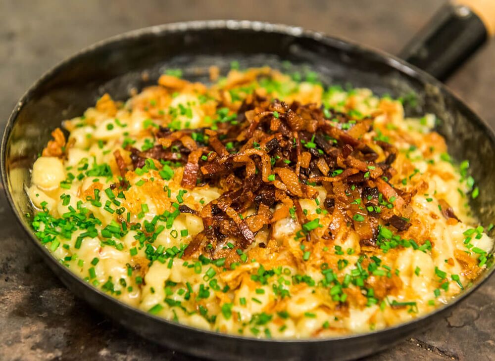 Käsespätzle mit braunem Butter und Zwiebeln in der gusseisernen Pfanne