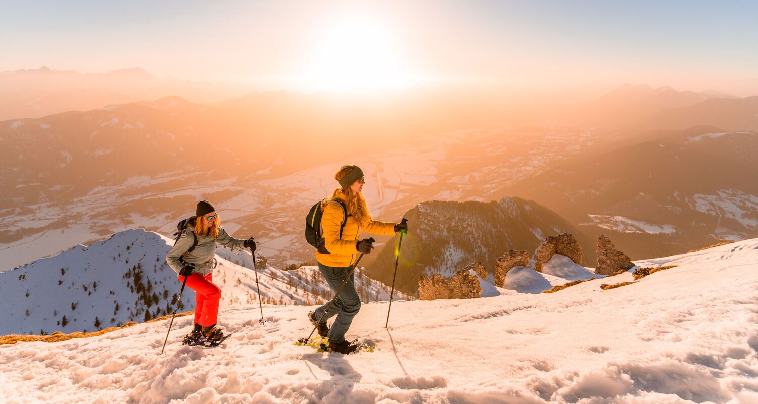 Two women during a scenic sunrise snowshoe tour through the snowy mountain landscape on the Dobratsch.
