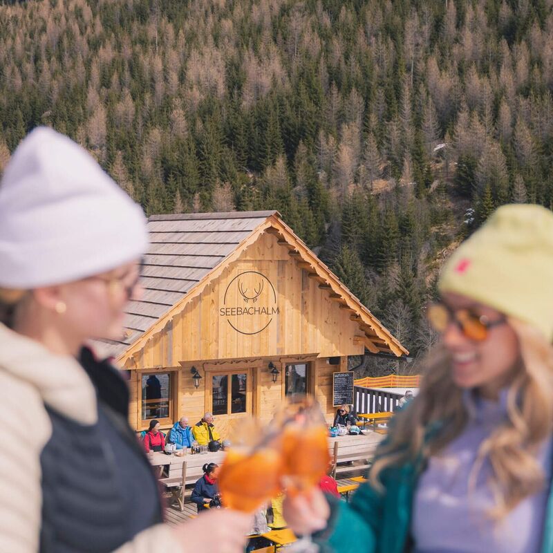 Zwei Damen stoßen mit einem Aperol auf der Seebachalm auf der Turracher Höhe an, sonniger Skitag