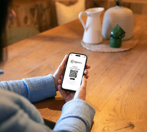 Frau hält ihr Handy mit dem Guest Mobility Ticket in der Hand.