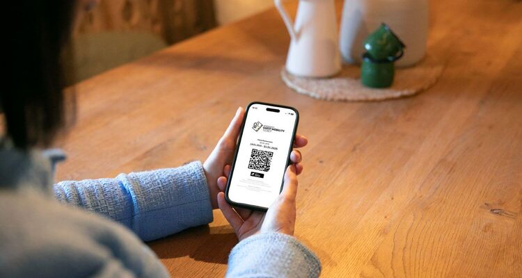 Vrouw houdt haar mobiele telefoon vast met het mobiliteitsticket voor gasten.