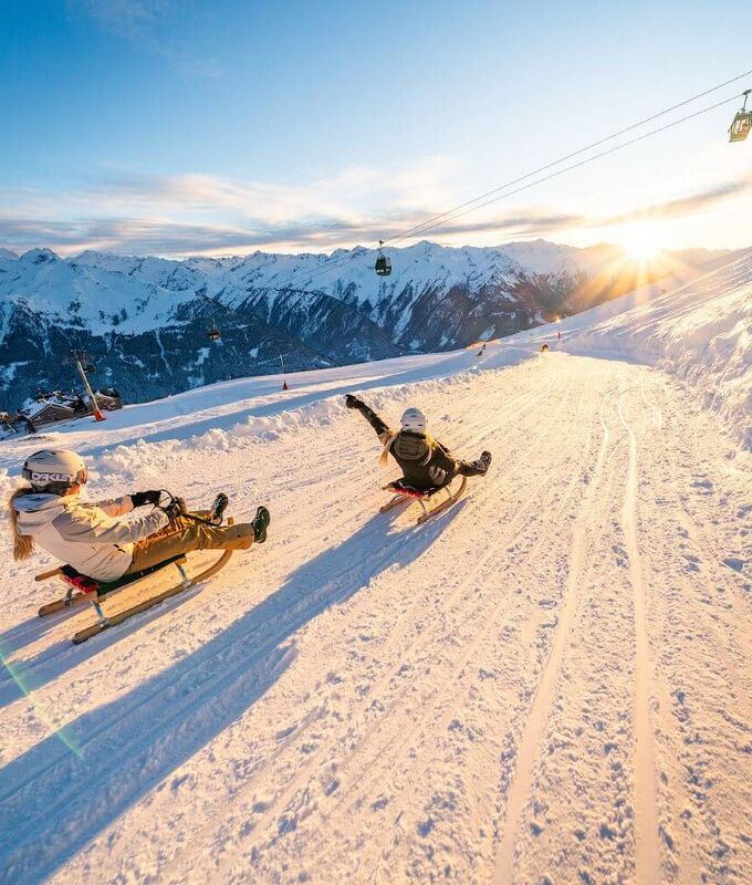 Zwei Schlittenfahrerinnen bei der Abfahrt auf der Wildkogel Rodelbahn