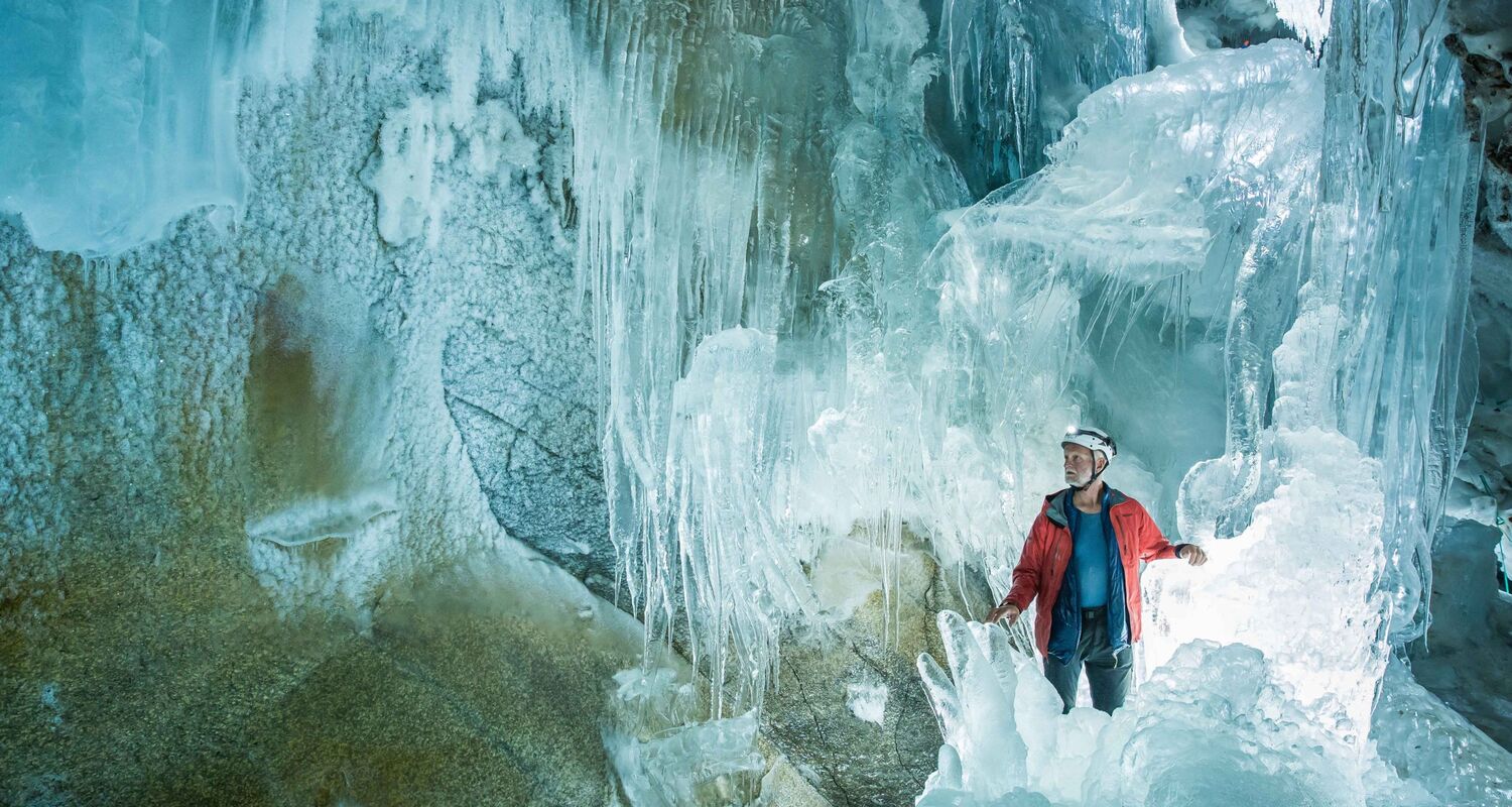 Blick in die Gletscherhöhle am Hintertuxer Gletscher im Zillertal, mit glitzernden Eisstalaktiten und gefrorenem Wasserfall.