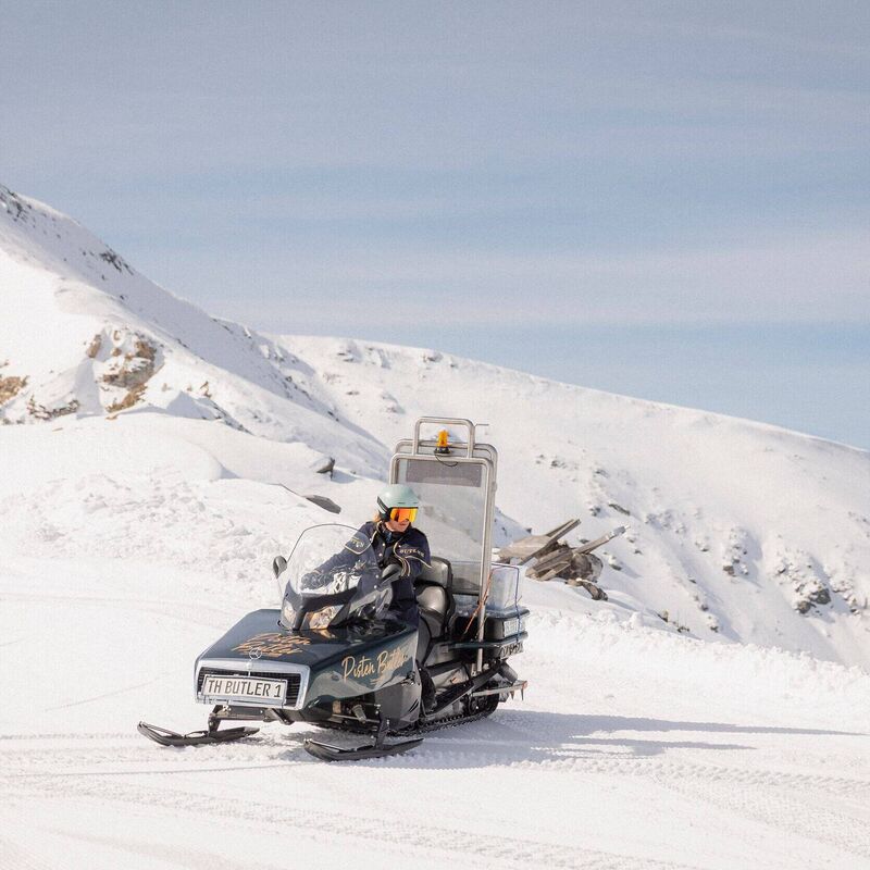Ein Pistenbutler fährt mit einem Skidoo über die verschneiten Hänge der Turracher Höhe unter strahlend blauem Himmel
