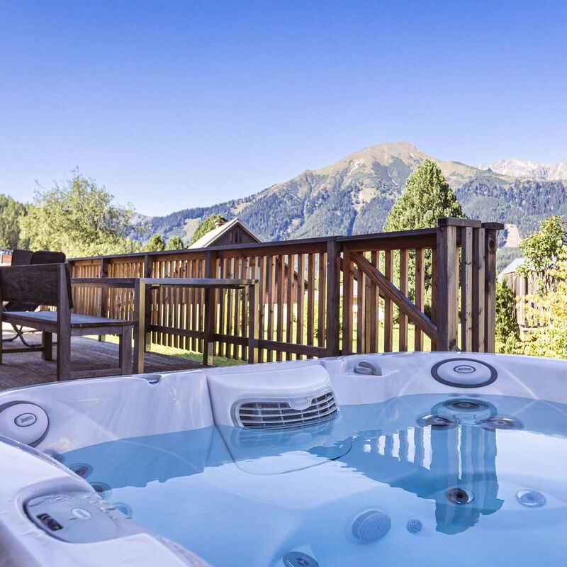 Terrasse eines Ferienhauses mit Whirlpool, Bergblick und Terrassenmöbel aus Holz