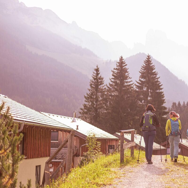 Gruppe von Wanderern spaziert zwischen Ferienhäusern