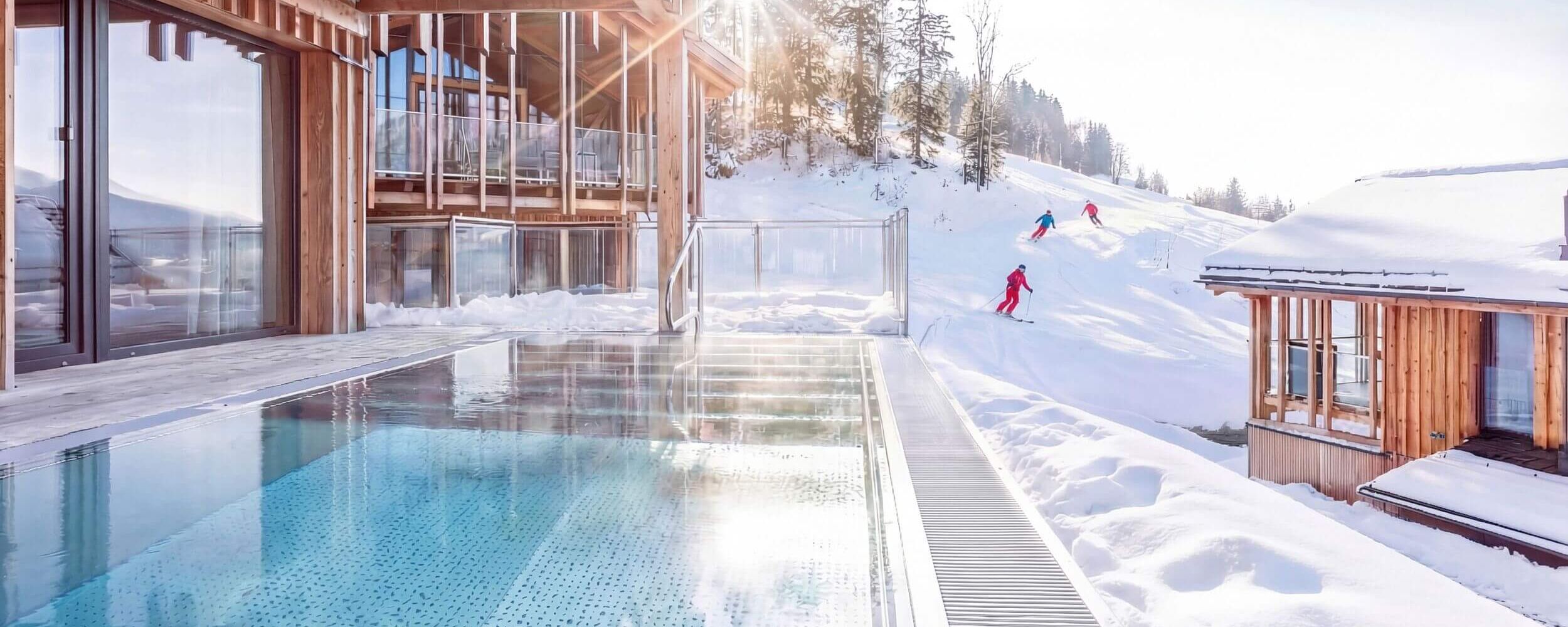 Verschneites Ferienhaus mit privatem Pool und Skifahrer im Hintergrund