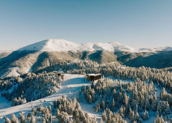 Skipiste schlängelt sich durch tiefverschneite Wälder im schneesicheren Skigebiet Turracher Höhe