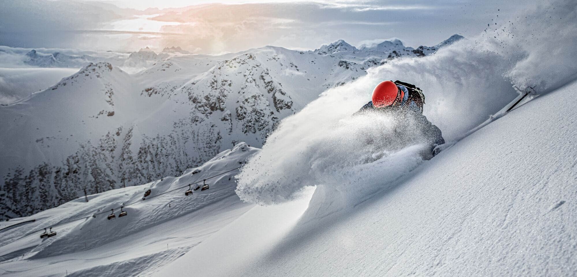 Freerider bei der Abfahrt im Pulverschnee, im Hintergrund eine moderne Sesselbahn