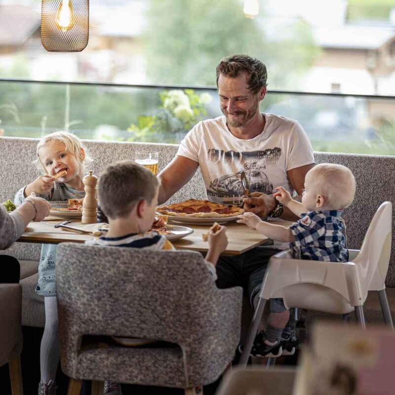 Junge Familie mit 3 kleinen Kindern sitzt am Tisch in einem Restaurant