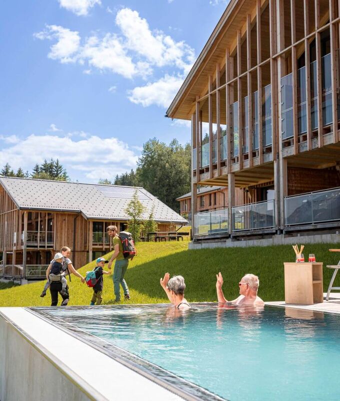 Grandparents wave to the wandering young family from the private pool of their holiday home.