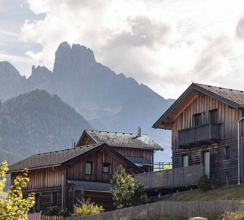 Drei Ferienhäuser im alpinen Stil vor der markanten Bergkulisse des Salzburger Landes