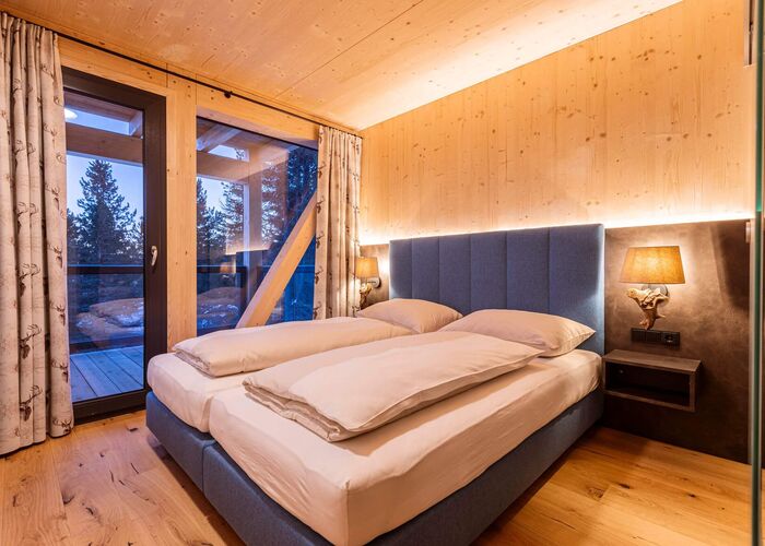 Schlafzimmer in einem Naturchalet auf der Turracher Höhe mit komfortablem Doppelbett, Holzelementen und alpiner Einrichtung für erholsamen Chalet-Urlaub in den Bergen.