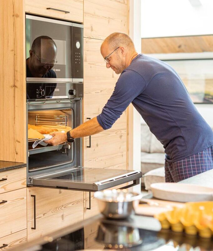 A man takes freshly baked rolls out of the oven for breakfast.