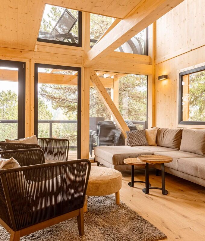 Cosy living area with glass front and view of the Swiss stone pine forest