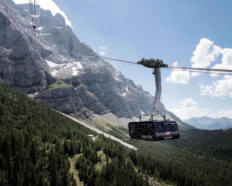 A modern verglaste Panoramagondel of the Zugspitz-Pendelbahn ascends towards Zugspitze's stunning peaks.