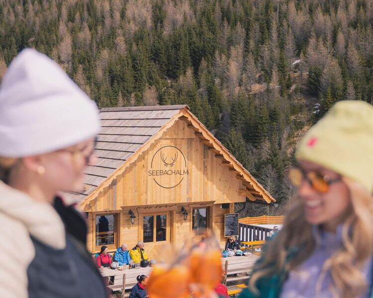 Zwei Damen stoßen mit einem Aperol auf der Seebachalm auf der Turracher Höhe an, sonniger Skitag