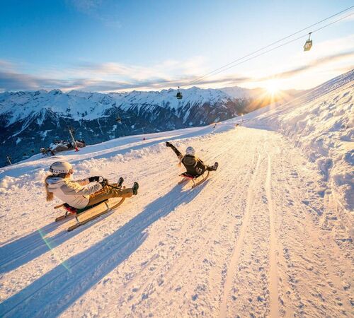 Zwei Schlittenfahrerinnen bei der Abfahrt auf der Wildkogel Rodelbahn