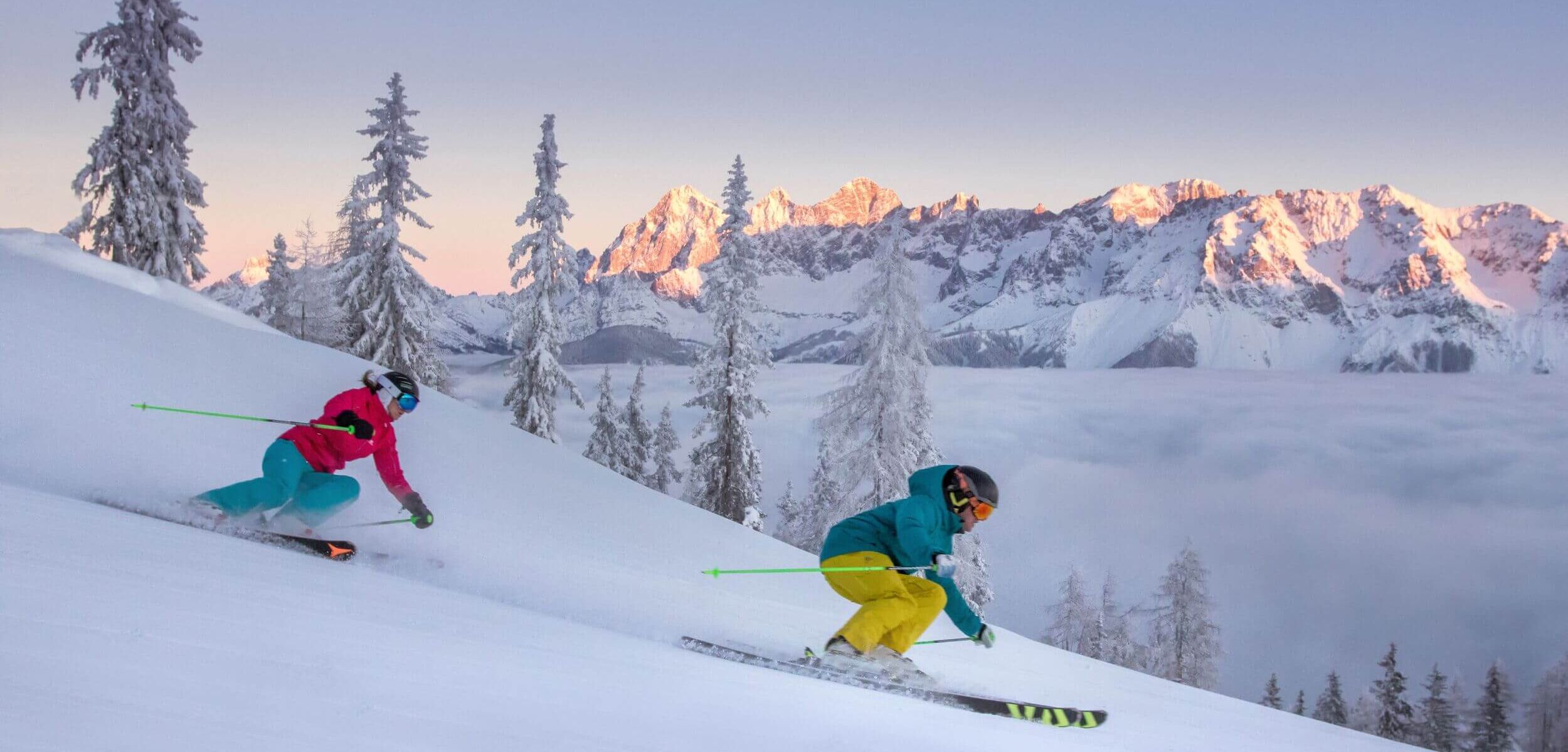 Zwei Skifahrer über der Nebelgrenze im Skigebiet Hochwurzen mit Blick auf den Dachstein