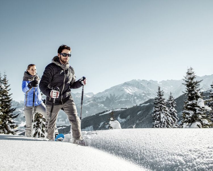 Snowshoe hiking through a snowy winter landscape with an impressive mountain panorama in the background.