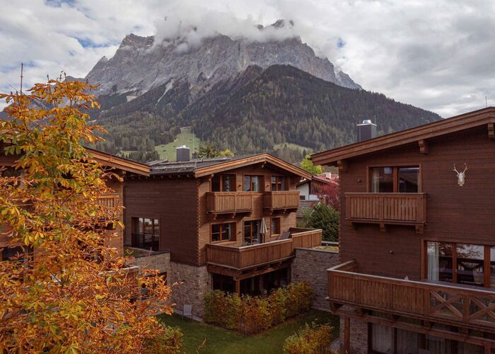Herbstliche Umgebung mit Holzhäusern und majestätischen Bergen unter bewölktem Himmel in der Nähe von bze fta.