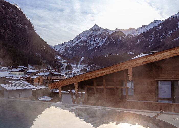 Infinity pool with rising smoke and a view of the Kitzsteinhorn
