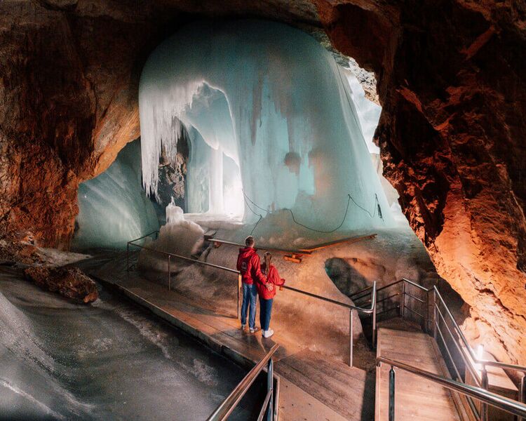Couple admiring a huge ice formation in the Eisriesenwelt ice caves.