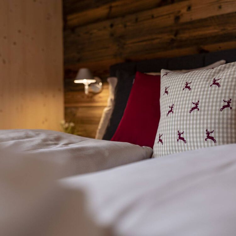 Knus, knus bed met kussens in een slaapkamer met houten lambrisering in alpine stijl