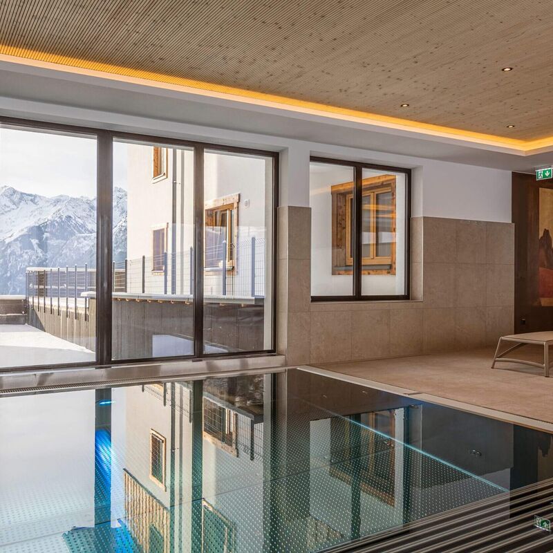 Indoor pool with cozy chair and unique view to the Tauern