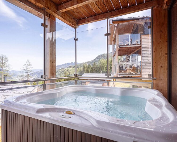 A luxurious hot tub sits in a wooden enclosure, offering stunning mountain views and a serene escape.