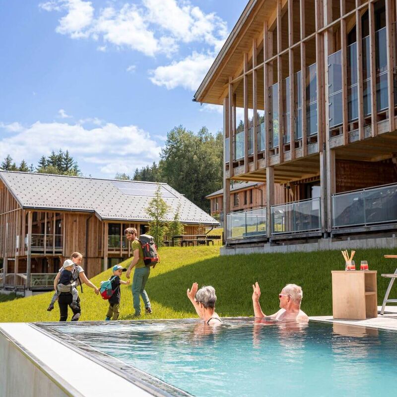 Grandparents wave to the wandering young family from the private pool of their holiday home.