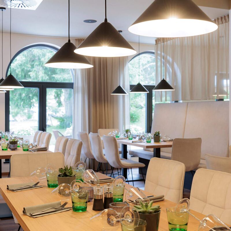 Laid tables with pendant lights in the Alps Kitchen restaurant at Bergresort Berwanger Hof