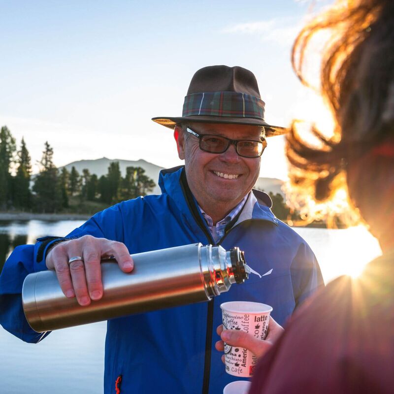 Almbutler serviert Tee bei Sonnenuntergang