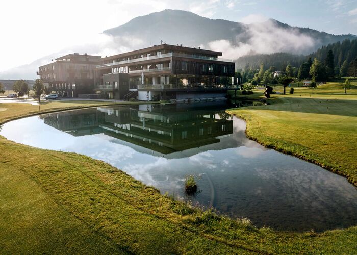 Das Berg & Golf Resort Westendorf spiegelt sich im Teich und bietet eine idyllische Umgebung in den Alpen.