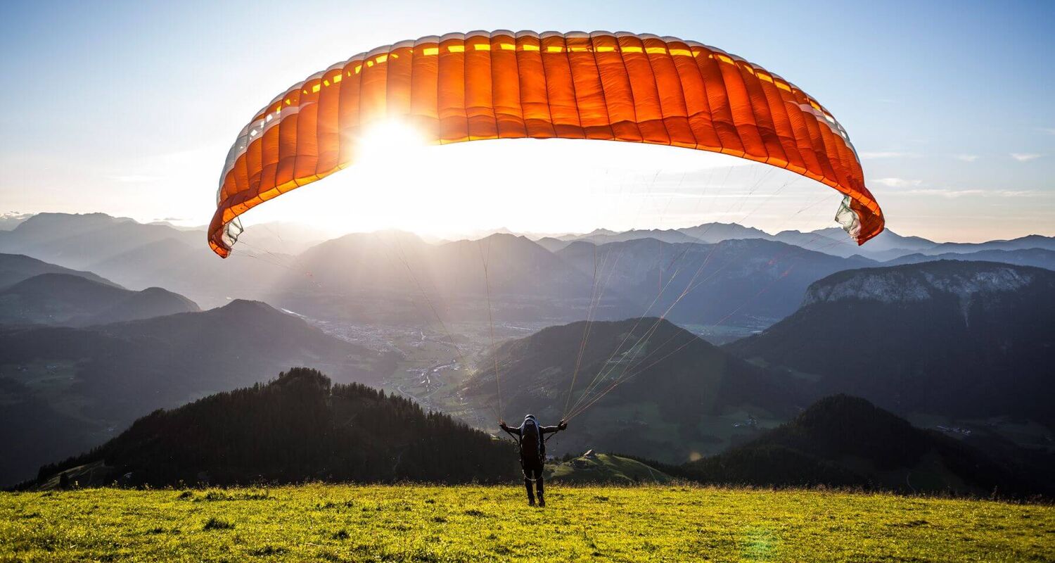 Paragleiter beim Start über Westendorf mit Blick auf die Tiroler Alpen