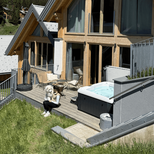 Hund liegt neben dem Whirlpool vor dem Chalet in den Bergen.